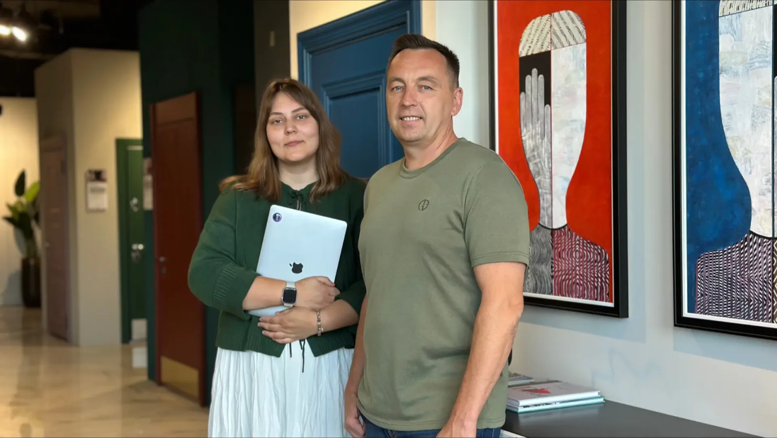 Сотрудники 'Дверного сезона' в креативном офисе с MacBook и абстрактными картинами